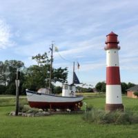 Liegt auf dem Trockenen, sieht aber trotzdem gut aus. Ein Fischkutter Kutter mit Leuchtturm